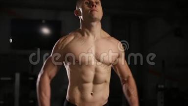 有<strong>起伏</strong>肌肉的人在健身房里用哑铃做练习。